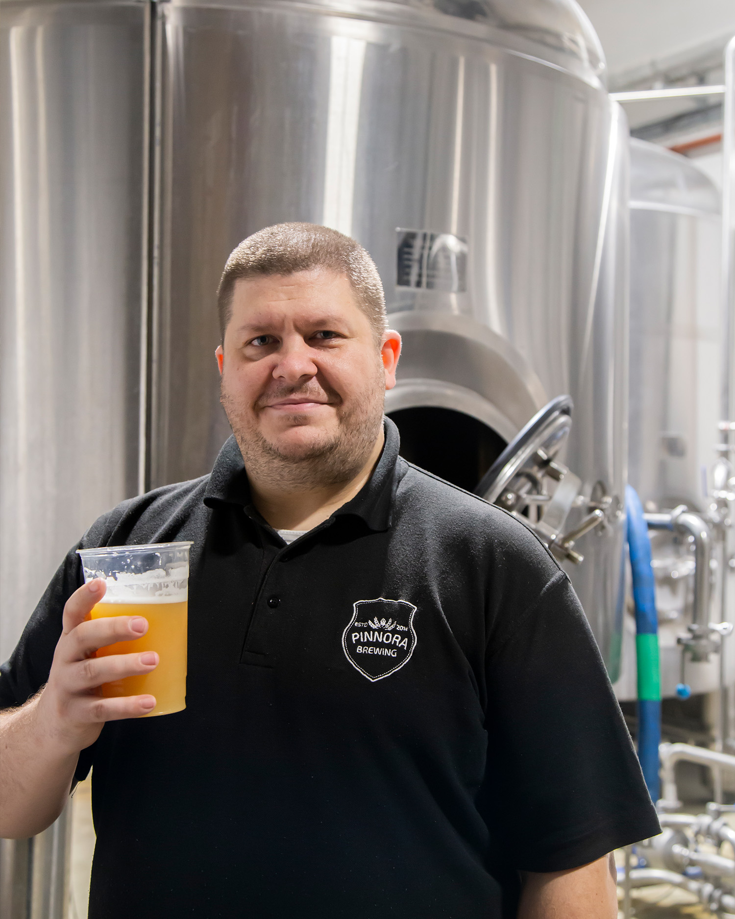 Gawain stood in front of Pinnora Brewing equipment close-up - steel kettles and fermentation tanks